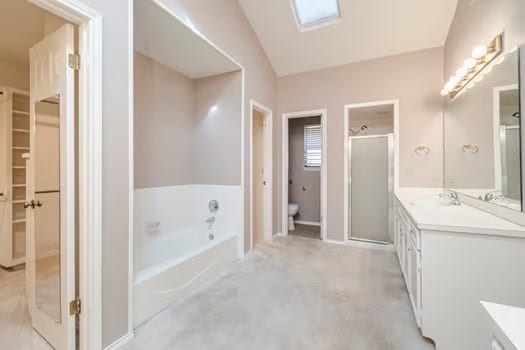 full bathroom with shower with separate bathtub, vanity, toilet, and vaulted ceiling with skylight