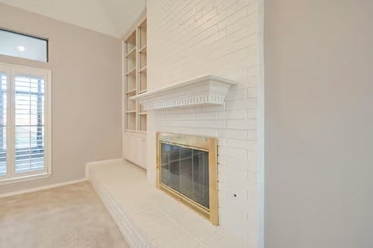 interior details featuring carpet flooring, built in shelves, and a brick fireplace