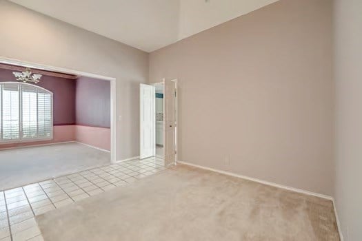 carpeted spare room featuring a chandelier