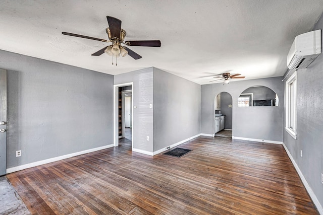 2109 Holloway Ave, Midland, TX 79705 - unfurnished living room featuring an AC wall unit, ceiling fan, arched walkways, dark wood-type flooring, and a textured ceiling
