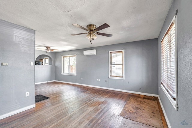 2109 Holloway Ave, Midland, TX 79705 - empty room featuring a wall unit AC, a ceiling fan, a textured ceiling, wood-type flooring, and baseboards