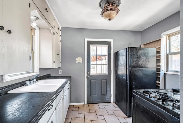 2109 Holloway Ave, Midland, TX 79705 - kitchen featuring black appliances, dark countertops, white cabinetry, light stone finish flooring, and baseboards