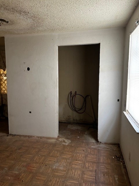 spare room with a textured ceiling and dark parquet floors