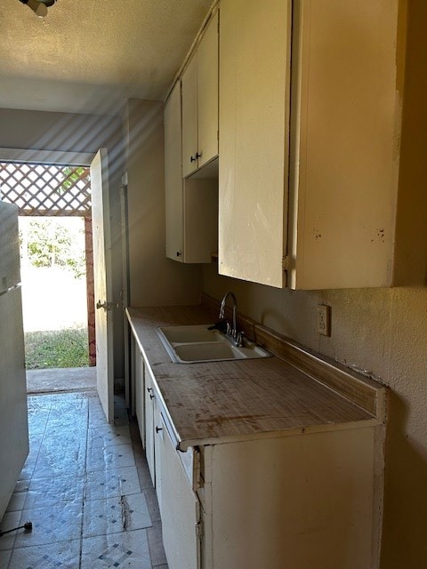 kitchen with white cabinetry, sink, and a textured ceiling