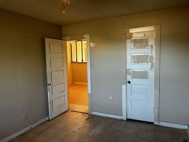 unfurnished room with ceiling fan and a textured ceiling