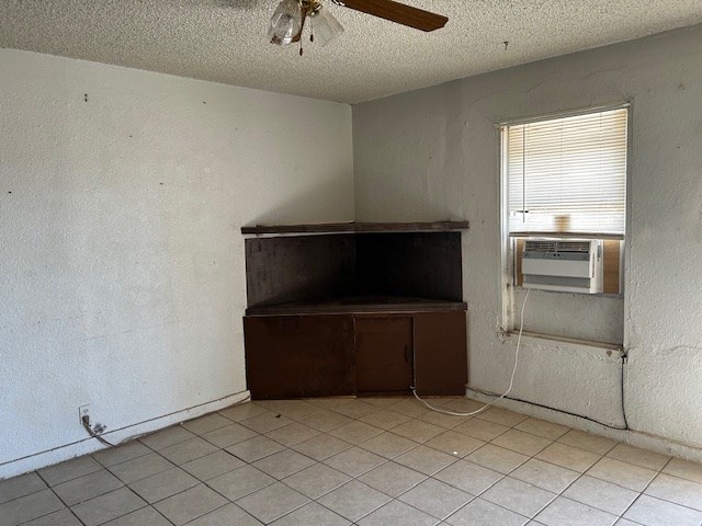 tiled spare room with ceiling fan, cooling unit, and a textured ceiling