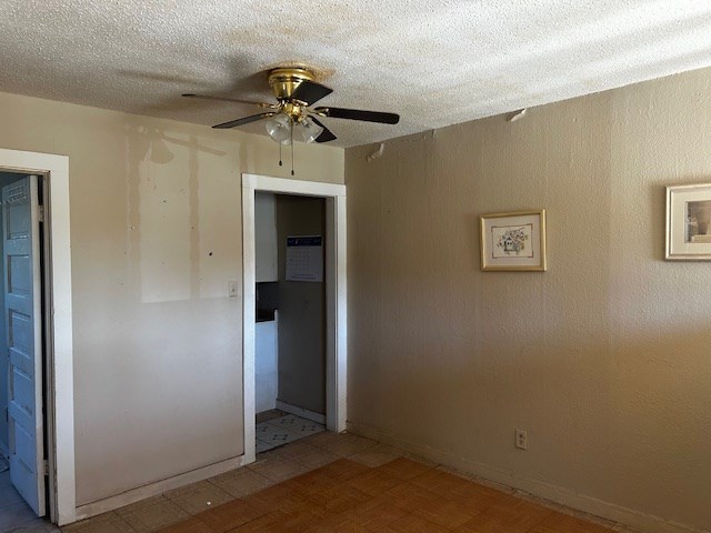 empty room with a textured ceiling and ceiling fan