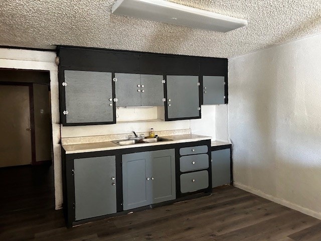 kitchen with a textured ceiling, dark hardwood / wood-style floors, gray cabinets, and sink