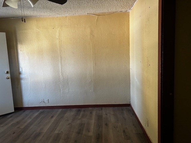 empty room with ceiling fan, dark hardwood / wood-style flooring, and a textured ceiling