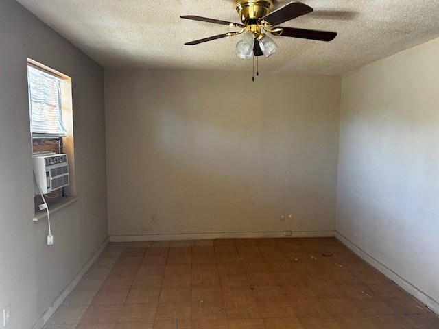 unfurnished room with ceiling fan, cooling unit, and a textured ceiling