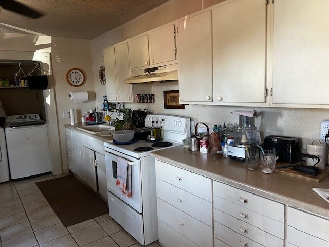 kitchen featuring a textured ceiling, sink, light tile patterned floors, electric range, and white cabinets