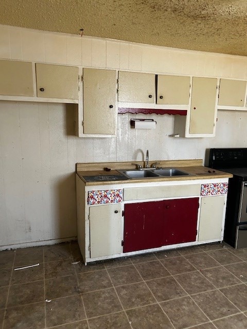 kitchen featuring cream cabinets, wood walls, sink, and black electric range