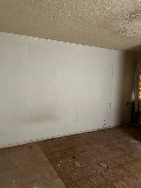 empty room featuring dark parquet floors and a textured ceiling