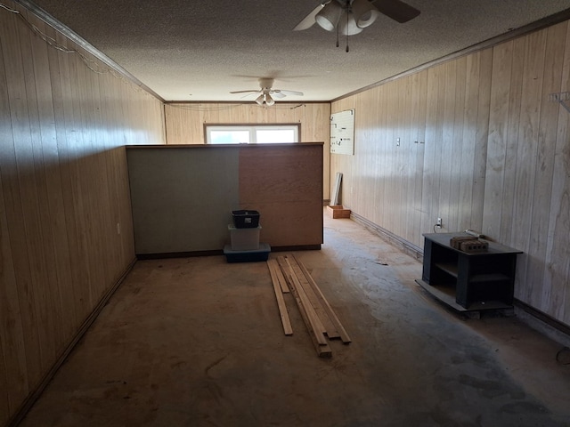 spare room featuring a ceiling fan, ornamental molding, wood walls, and a textured ceiling