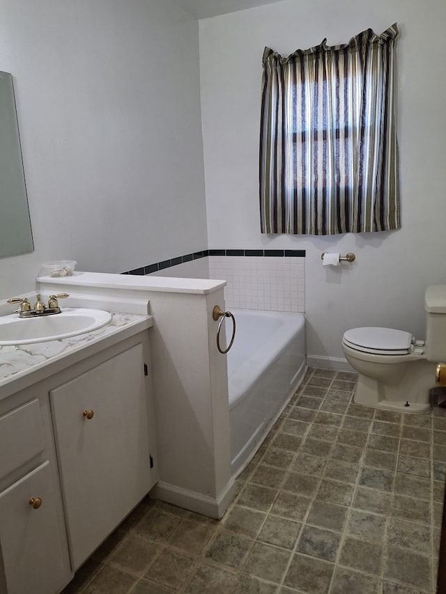 bathroom featuring toilet, vanity, and a garden tub