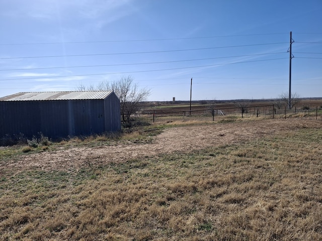 view of yard with an outbuilding, fence, a rural view, and a pole building