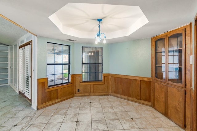 3400 Dentcrest Dr, Midland, TX 79707 - unfurnished dining area featuring a raised ceiling, a wainscoted wall, a chandelier, light tile patterned floors, and a skylight