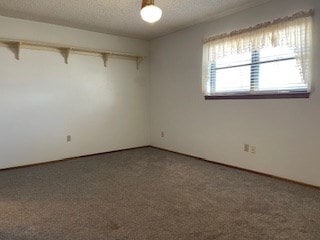 spare room with dark carpet and a textured ceiling