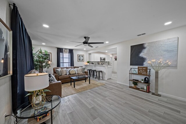 kitchen featuring white cabinets, light hardwood / wood-style flooring, a kitchen bar, kitchen peninsula, and stainless steel appliances