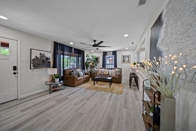 bedroom featuring ceiling fan, a barn door, ensuite bathroom, and light hardwood / wood-style flooring