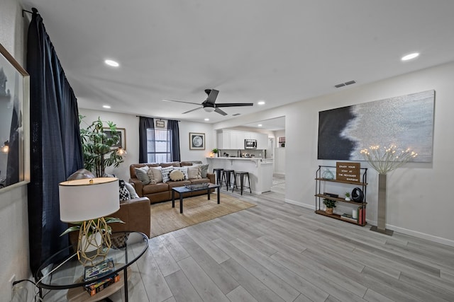 living room with light hardwood / wood-style flooring and ceiling fan