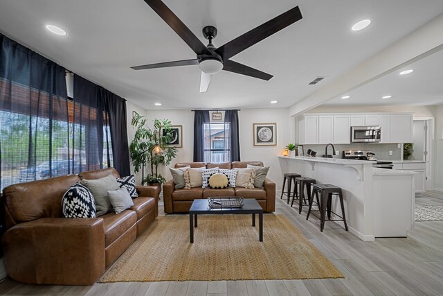 kitchen with backsplash, light hardwood / wood-style floors, light stone counters, white cabinetry, and stainless steel appliances