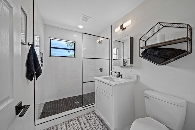 bathroom with vanity, toilet, and tiled shower