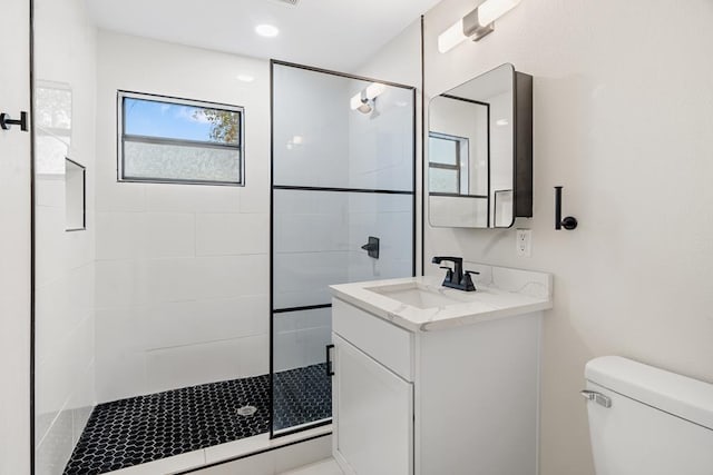 bathroom with vanity, toilet, and a tile shower