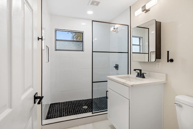 bathroom featuring tile patterned floors, vanity, toilet, and a shower with door