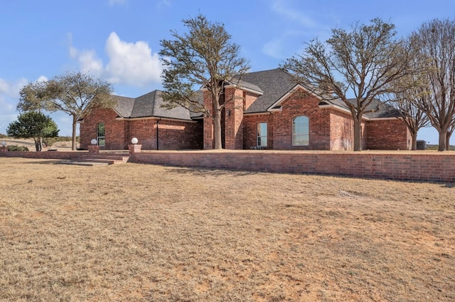 view of front of house featuring brick siding and a front lawn