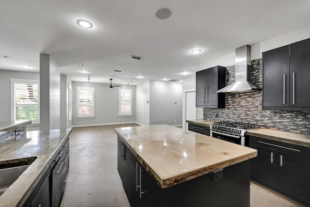 1 Lafayette Pl, Midland, TX 79705 - kitchen featuring wall chimney range hood, dark cabinetry, black range with gas cooktop, backsplash, and concrete floors