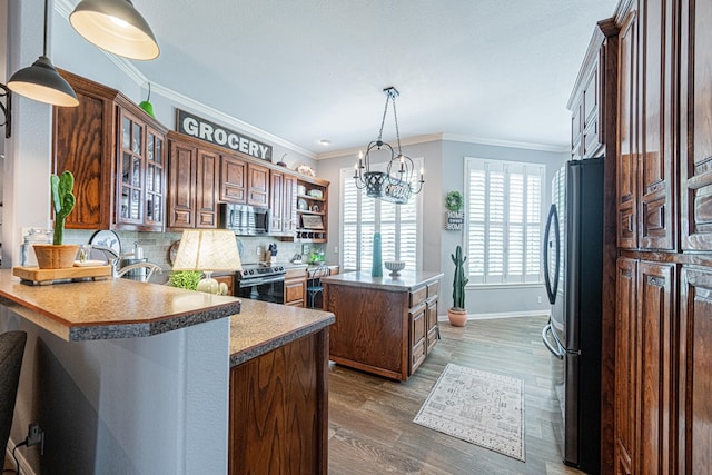2108 S County Rd 1086, Midland, TX 79706 - kitchen with stainless steel appliances, a center island, wood finished floors, a chandelier, and glass insert cabinets