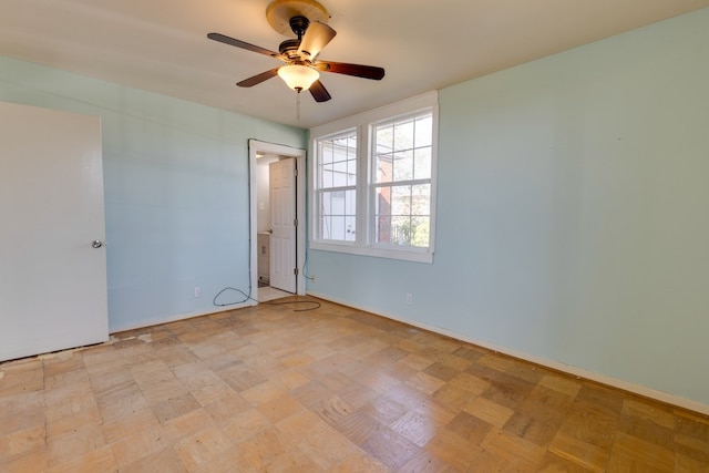 empty room with ceiling fan and baseboards