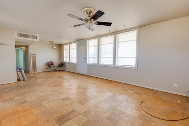 spare room with ceiling fan with notable chandelier, visible vents, and baseboards