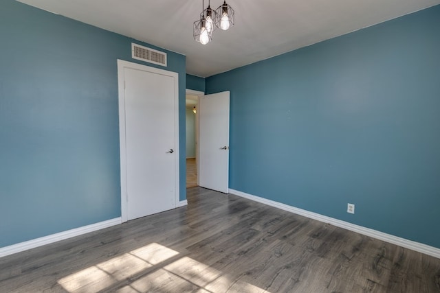 empty room with baseboards, visible vents, and wood finished floors