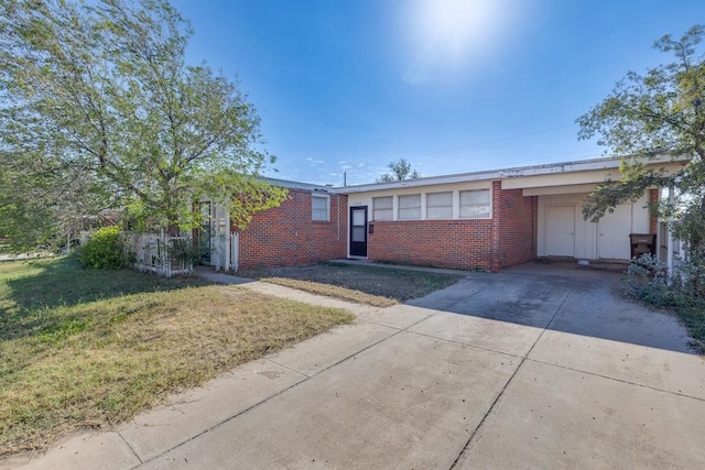 single story home with brick siding, a carport, a front yard, and concrete driveway