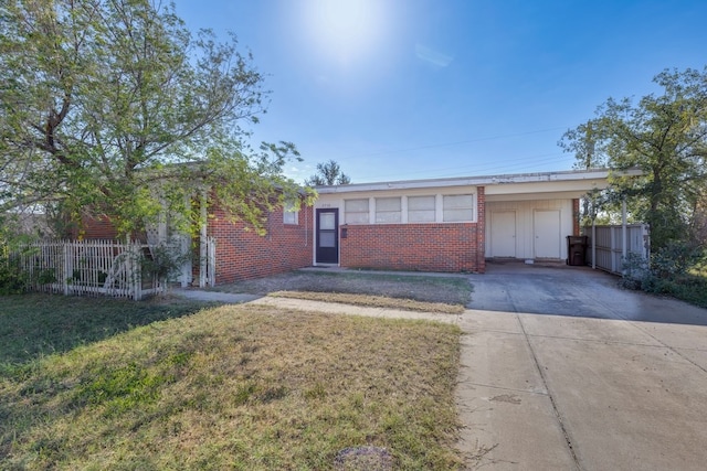 single story home with concrete driveway, a front yard, brick siding, and fence