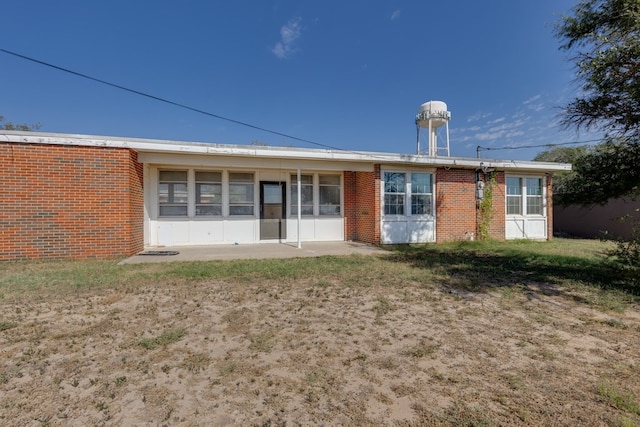 back of property featuring a patio and brick siding