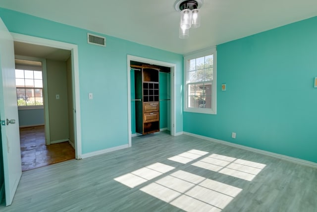 unfurnished bedroom with wood finished floors, visible vents, and multiple windows