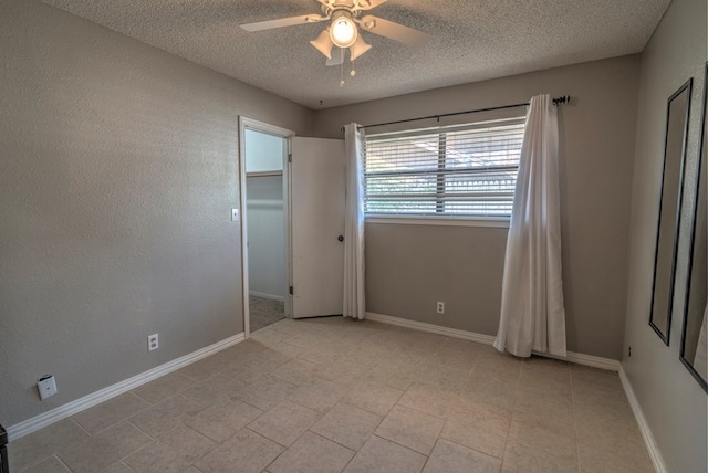 unfurnished bedroom featuring a textured ceiling, a ceiling fan, and baseboards