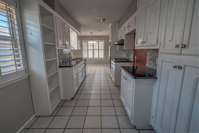 kitchen with open shelves, a textured ceiling, a chandelier, white cabinets, and light tile patterned floors