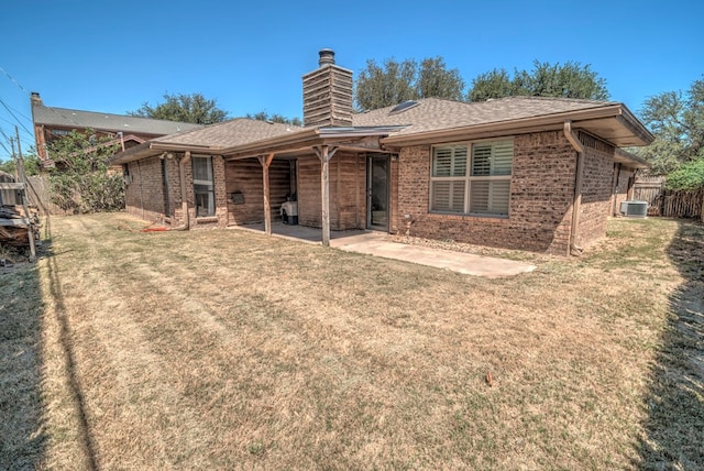 rear view of property with brick siding, central AC, a patio, a chimney, and a shingled roof