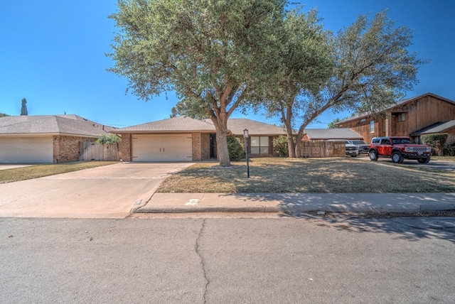 view of front of home with an attached garage, concrete driveway, brick siding, and fence