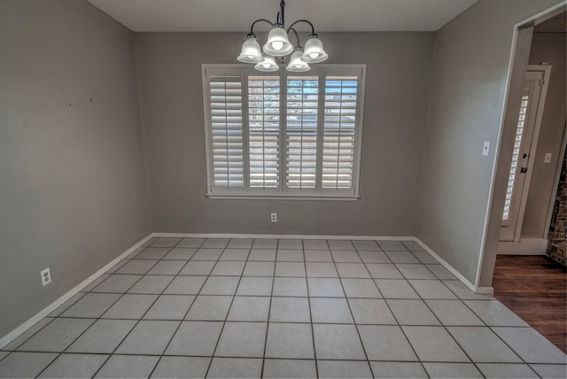 unfurnished dining area with a chandelier, baseboards, and light tile patterned flooring