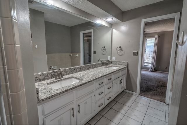 full bathroom with a textured ceiling, double vanity, and baseboards