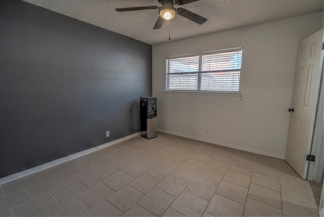 spare room featuring a ceiling fan, a textured ceiling, light tile patterned floors, and baseboards