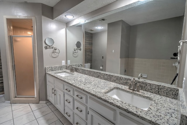 full bathroom featuring a shower stall, toilet, and double vanity