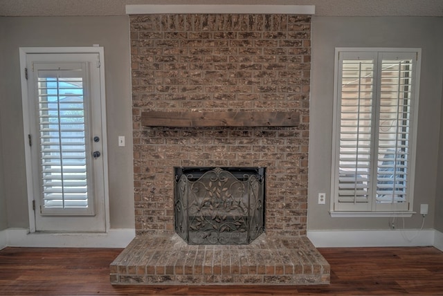 detailed view of wood finished floors, a fireplace, and a textured ceiling