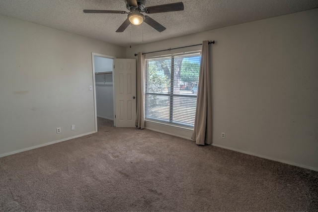 spare room with carpet flooring, a ceiling fan, a textured ceiling, and baseboards