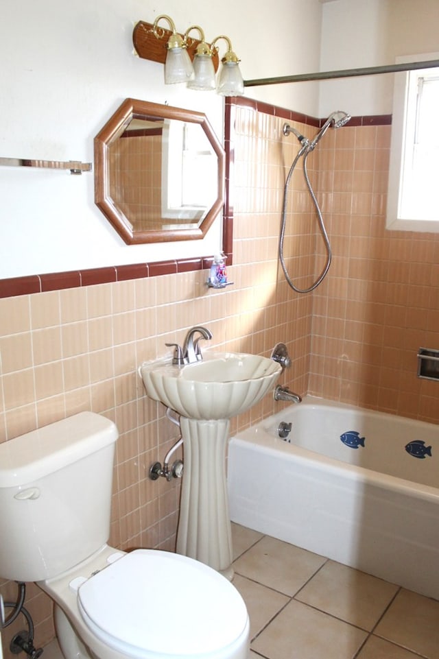 bathroom featuring tile patterned flooring, tiled shower / bath, toilet, and tile walls